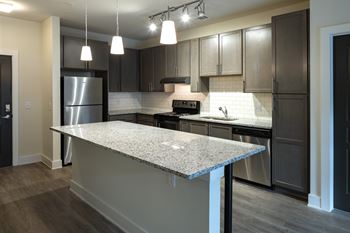 A kitchen with a granite countertop and stainless steel appliances.